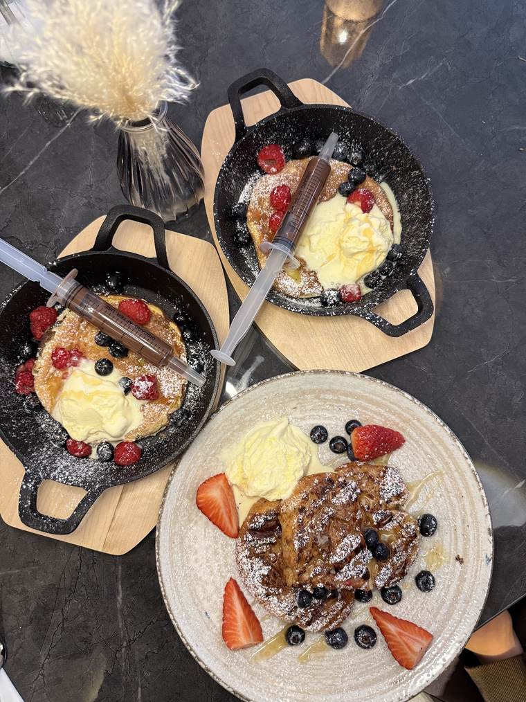 Pancakes in der Gusseisenpfanne mit Beeren, Eis und Schokoladensauce